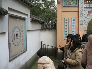 People tossing coins into the Wishing Wall Hole